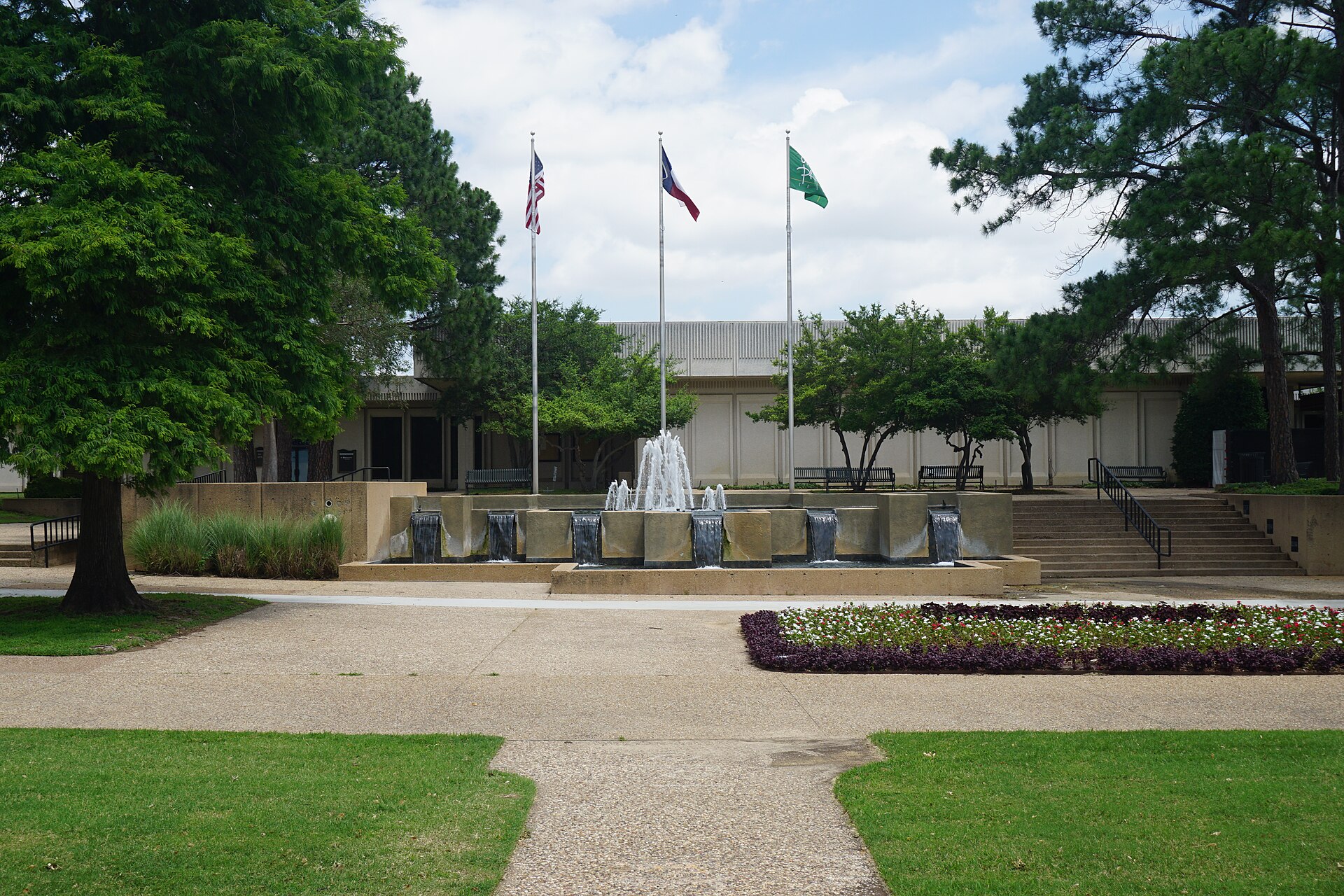 Grand Prairie City Hall plaza with a fountain and three flagpoles.