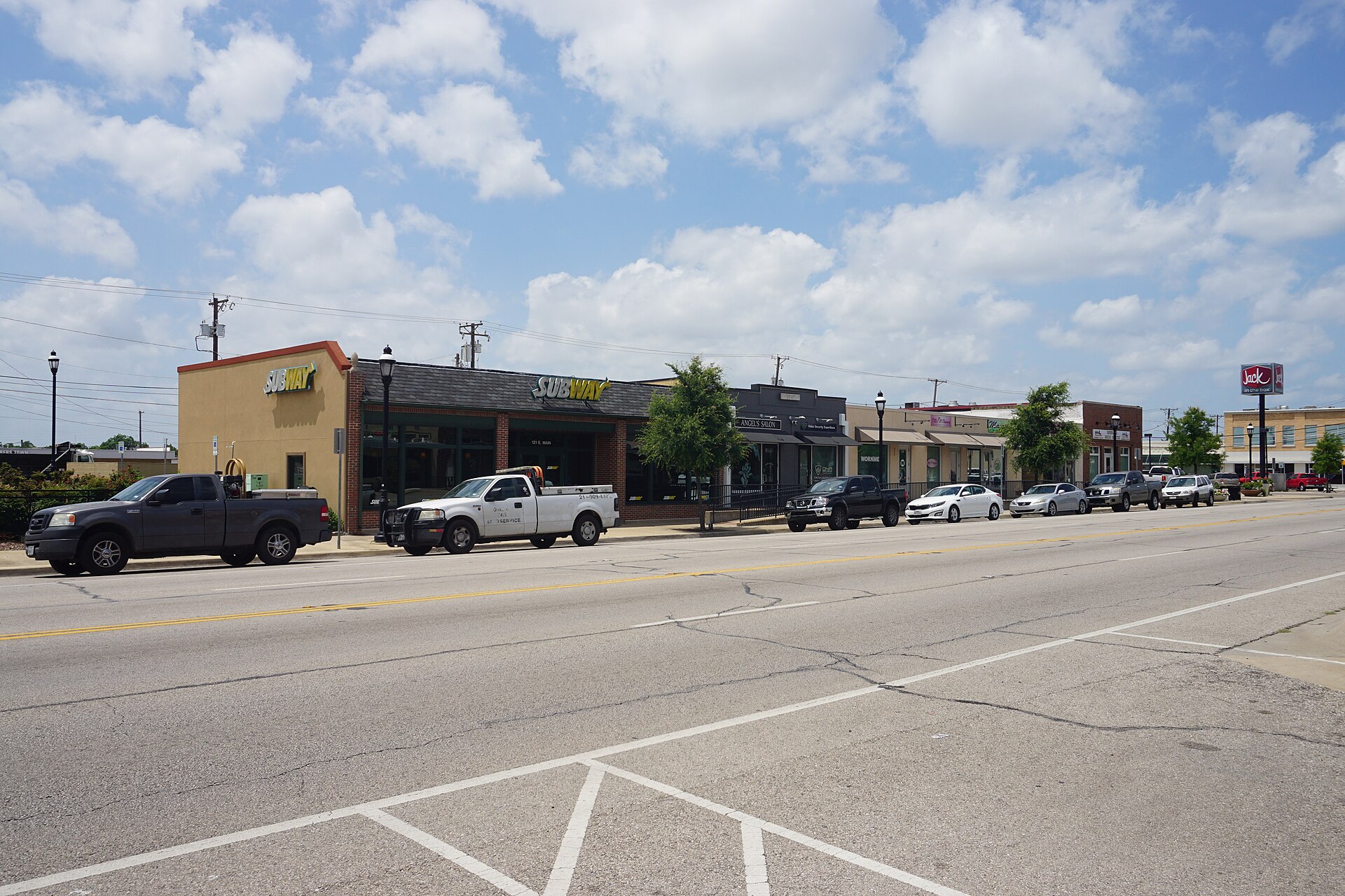 East Main Street in downtown Grand Prairie with storefronts and parked cars.
